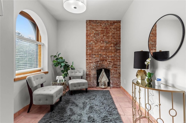 sitting room featuring light tile patterned floors and a brick fireplace