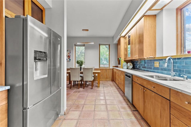 kitchen with sink, light tile patterned floors, tasteful backsplash, light stone counters, and stainless steel appliances