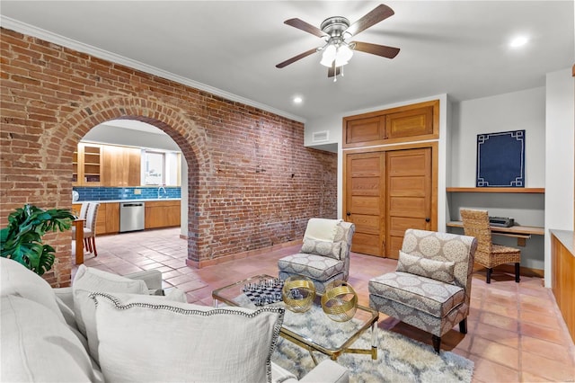 tiled living room featuring ceiling fan, brick wall, and ornamental molding