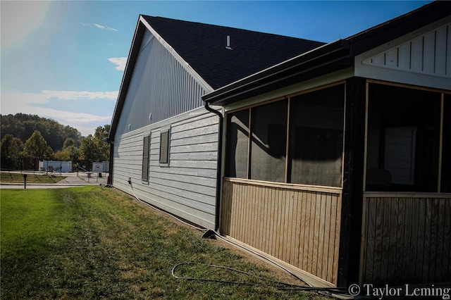 view of side of home with a sunroom and a lawn