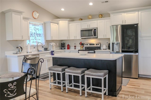 kitchen with lofted ceiling, white cabinetry, a center island, and stainless steel appliances