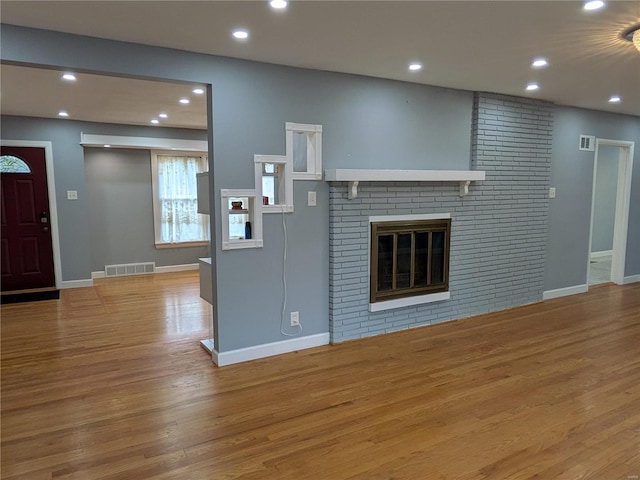 unfurnished living room with a brick fireplace and light wood-type flooring