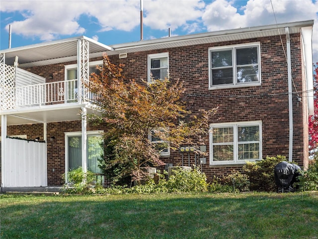 rear view of property with a lawn and a balcony