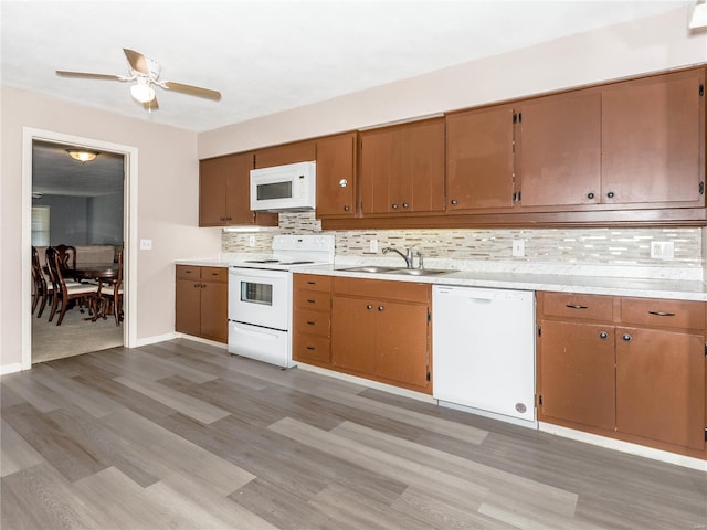 kitchen featuring white appliances, sink, light wood-type flooring, backsplash, and ceiling fan