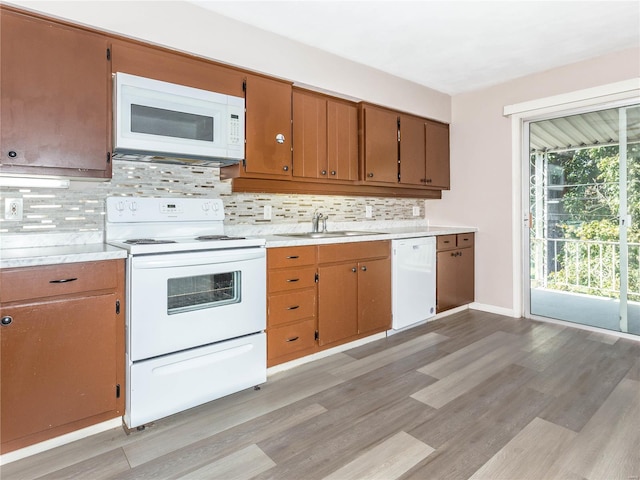 kitchen featuring white appliances, light hardwood / wood-style floors, decorative backsplash, and sink