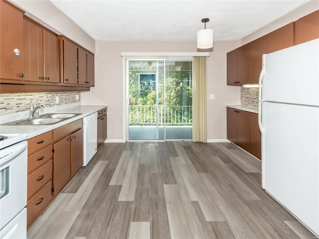 kitchen featuring sink, decorative light fixtures, light wood-type flooring, white appliances, and tasteful backsplash