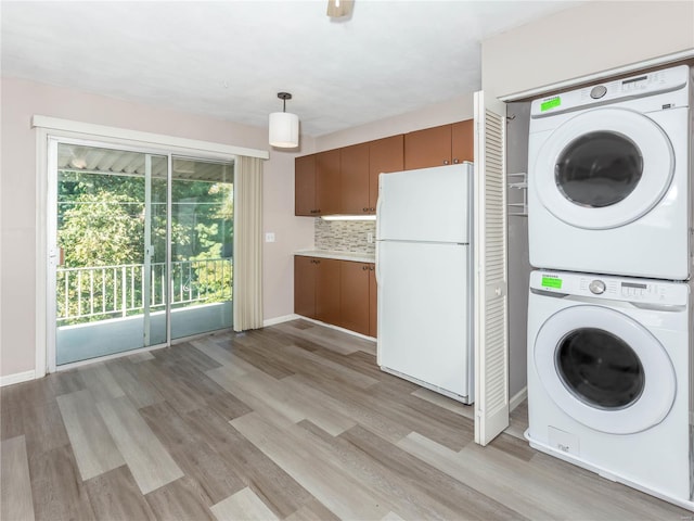 laundry room featuring stacked washer / drying machine and light hardwood / wood-style flooring