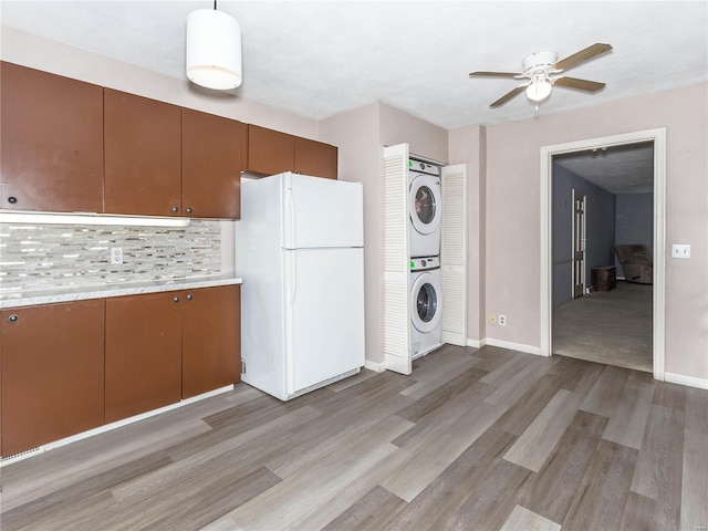 laundry room featuring ceiling fan, light hardwood / wood-style floors, and stacked washing maching and dryer