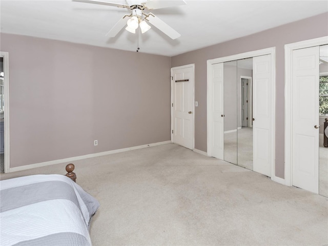 bedroom with ceiling fan, two closets, and light colored carpet