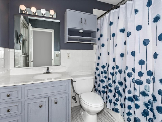 bathroom with a shower with shower curtain, toilet, tile patterned floors, tile walls, and vanity