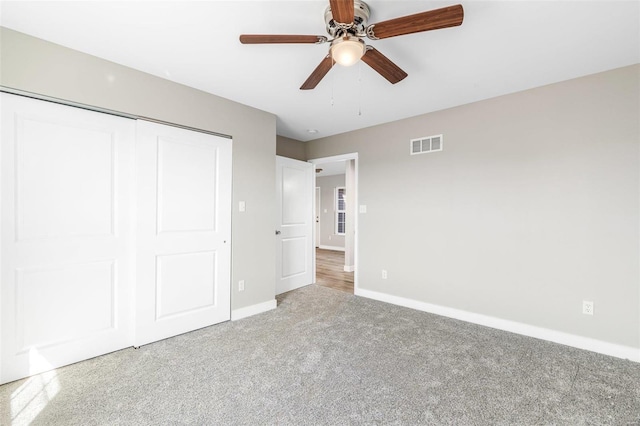 unfurnished bedroom featuring a closet, light colored carpet, and ceiling fan