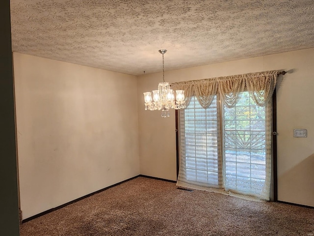 empty room featuring carpet, a textured ceiling, and a chandelier