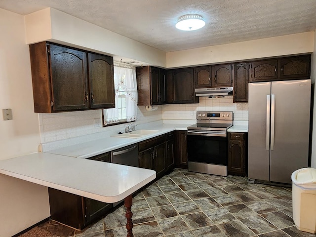 kitchen featuring kitchen peninsula, decorative backsplash, appliances with stainless steel finishes, dark brown cabinetry, and sink