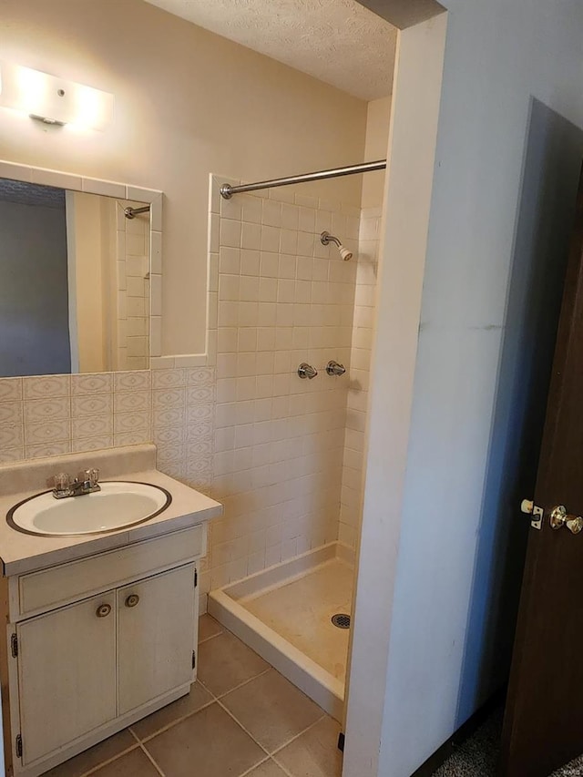 bathroom with tiled shower, tile patterned floors, tile walls, vanity, and a textured ceiling