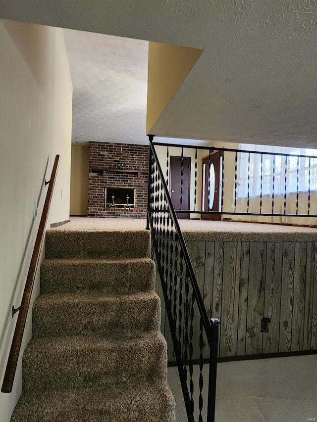 staircase featuring a brick fireplace and a textured ceiling