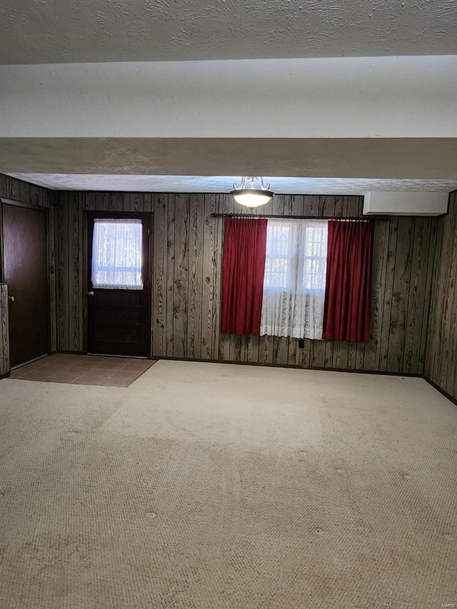 carpeted spare room featuring wooden walls