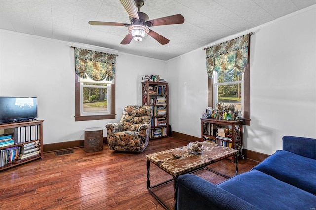 living room with ceiling fan, a healthy amount of sunlight, wood-type flooring, and ornamental molding