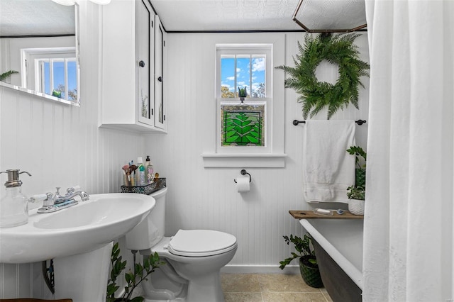 bathroom with toilet, a textured ceiling, and tile patterned flooring