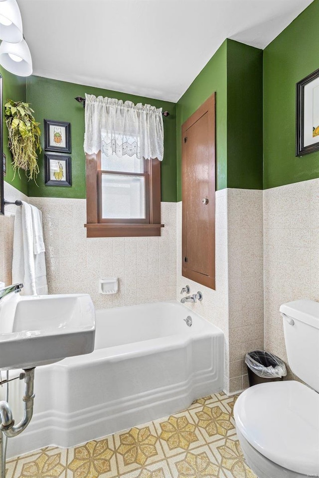 bathroom with toilet, tile walls, and a tub