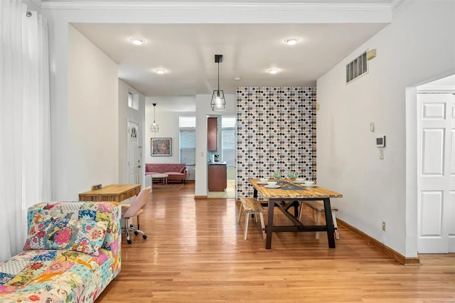 dining area featuring ornamental molding and light hardwood / wood-style flooring