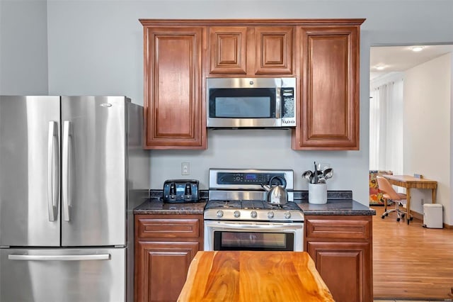 kitchen with hardwood / wood-style flooring, stainless steel appliances, and dark stone counters