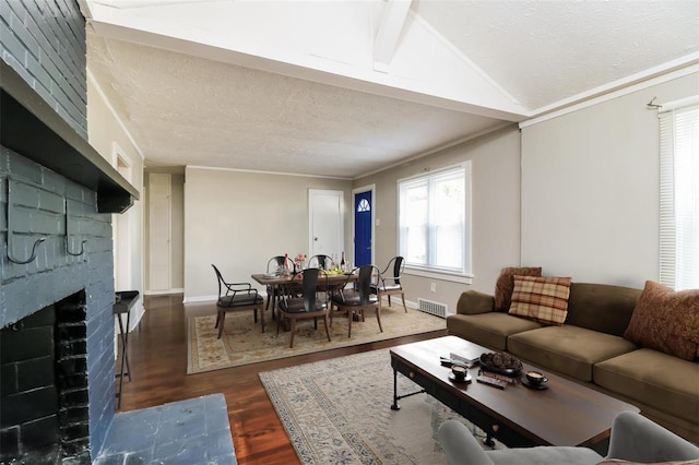 living room featuring vaulted ceiling with beams, a healthy amount of sunlight, dark wood-type flooring, and a brick fireplace