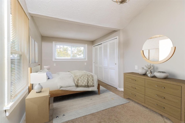 carpeted bedroom featuring a textured ceiling and a closet