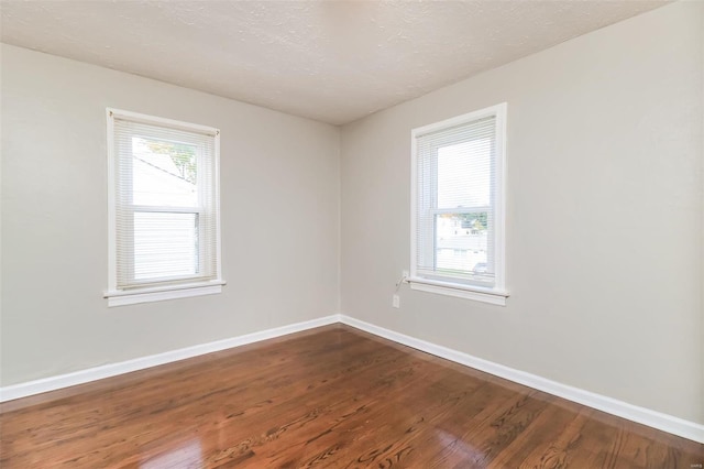 unfurnished room featuring a textured ceiling and dark hardwood / wood-style flooring