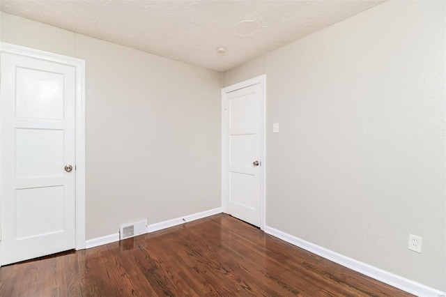 spare room with dark hardwood / wood-style floors and a textured ceiling