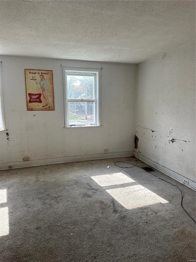 carpeted empty room with a textured ceiling