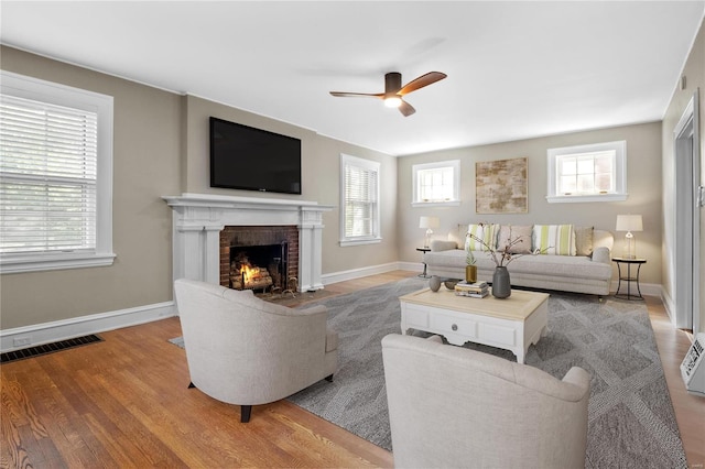 living room with hardwood / wood-style floors, ceiling fan, and a brick fireplace