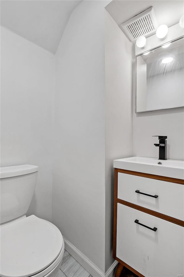 bathroom featuring vanity, lofted ceiling, and toilet