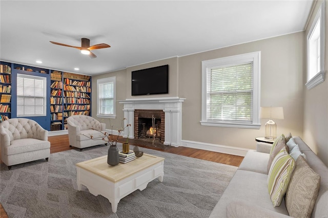 living room featuring light hardwood / wood-style floors, a fireplace, plenty of natural light, and ceiling fan