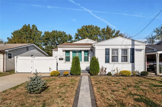 bungalow-style home with driveway, a gate, fence, and a front lawn