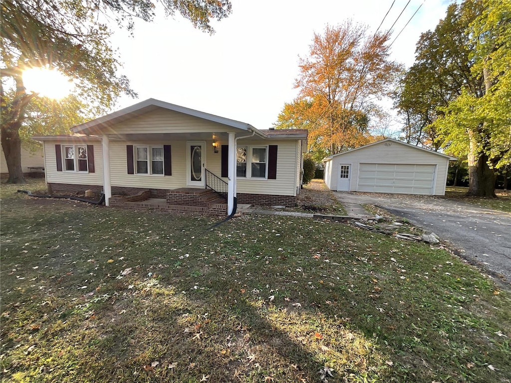 single story home with a garage, a front lawn, an outbuilding, and a porch