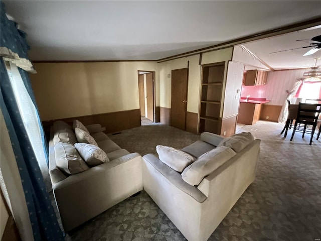 living room featuring lofted ceiling, crown molding, carpet floors, and ceiling fan