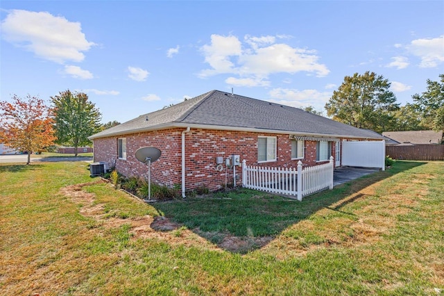 back of house with central air condition unit and a lawn