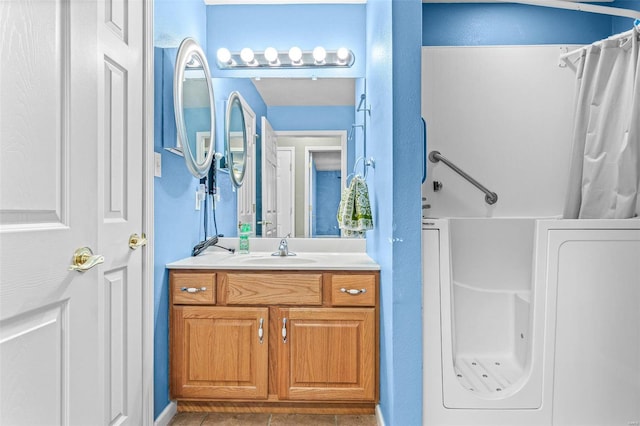 bathroom featuring washer / dryer, vanity, curtained shower, and tile patterned floors