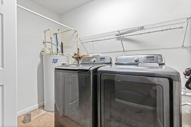 laundry area with water heater, washing machine and clothes dryer, and light tile patterned floors