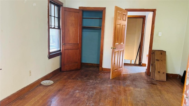 unfurnished bedroom featuring dark wood-type flooring and multiple windows