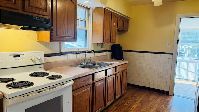 kitchen featuring range hood, sink, white range with electric stovetop, tile walls, and dark hardwood / wood-style flooring