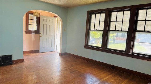 empty room with hardwood / wood-style flooring, a textured ceiling, and an inviting chandelier