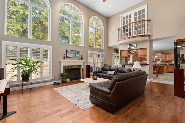 living room with a premium fireplace, a high ceiling, and light hardwood / wood-style floors