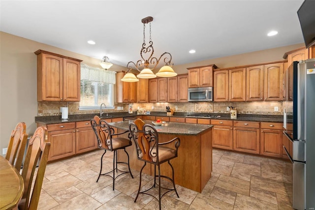 kitchen featuring decorative backsplash, a kitchen island, appliances with stainless steel finishes, an inviting chandelier, and decorative light fixtures