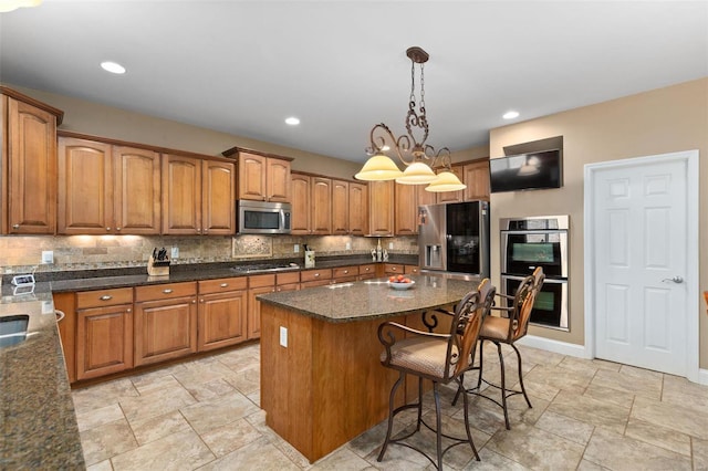 kitchen featuring appliances with stainless steel finishes, a center island, hanging light fixtures, decorative backsplash, and a chandelier