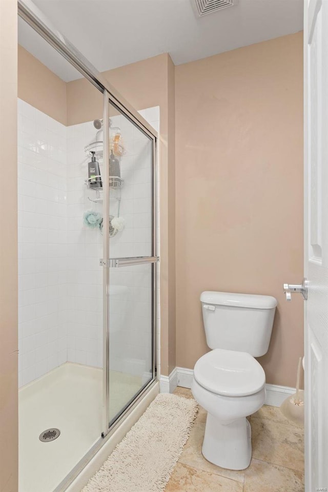 bathroom with toilet, tile patterned flooring, and a shower with door