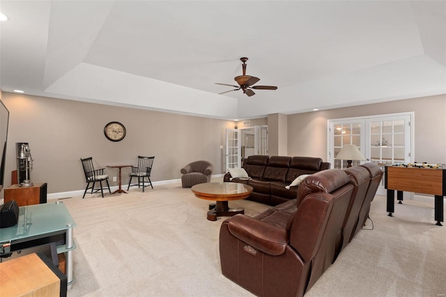 living room featuring french doors, light carpet, a tray ceiling, and ceiling fan