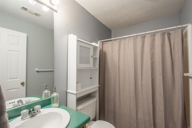 bathroom featuring toilet, a textured ceiling, a shower with curtain, and vanity