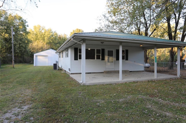 view of front of property featuring central air condition unit, a front lawn, an outbuilding, and a garage