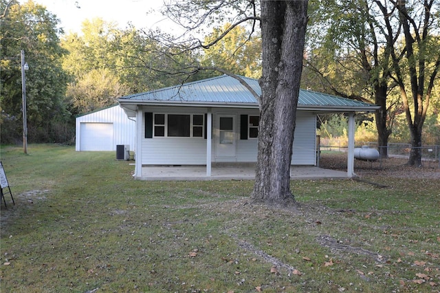 view of front of home featuring a front yard, an outdoor structure, a garage, and central AC unit